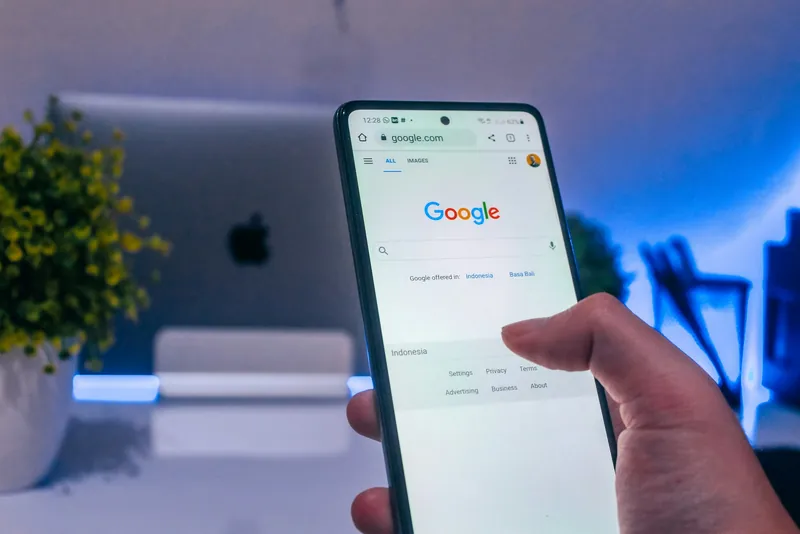 Een hand houdt een telefoon vast met de zoekpagina van Google open